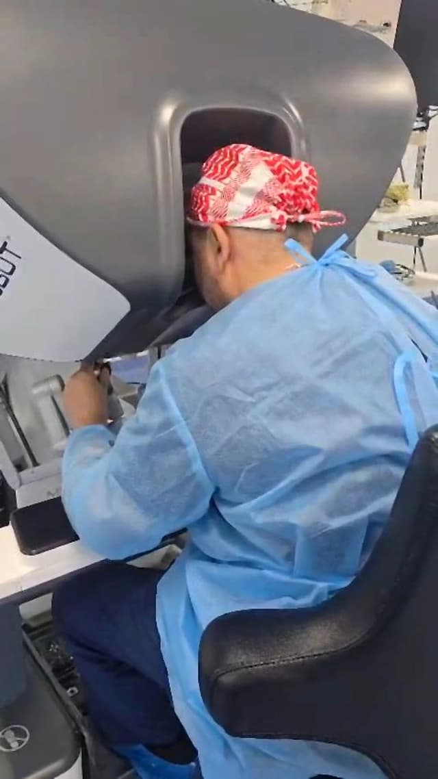 Dr. Mohammad Al-Zaitawi precisely controlling the surgical robot's arms from the console