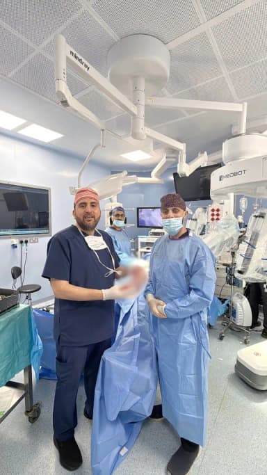 الدكتور محمد عبد الوهاب الزيتاوي مع أحد أعضاء الفريق الجراحي في غرفة العمليات الروبوتية بالمستشفى التخصصي بعد أول عملية تكميم معدة بالروبوت في الأردن